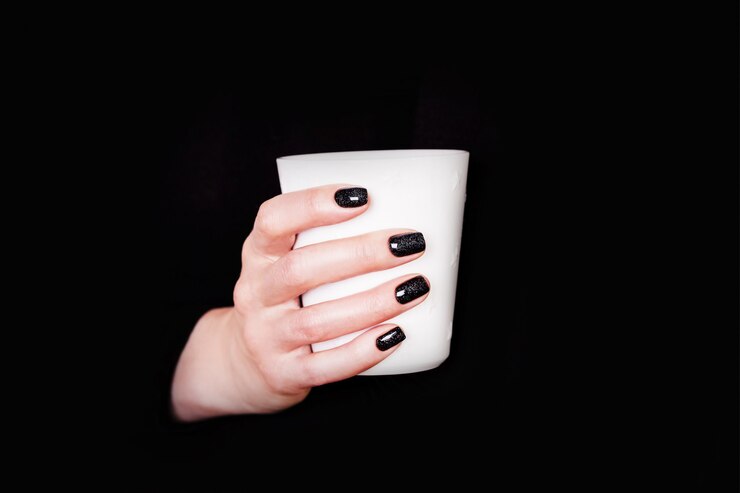 Foto mãos segurando um copo branco manicure preto