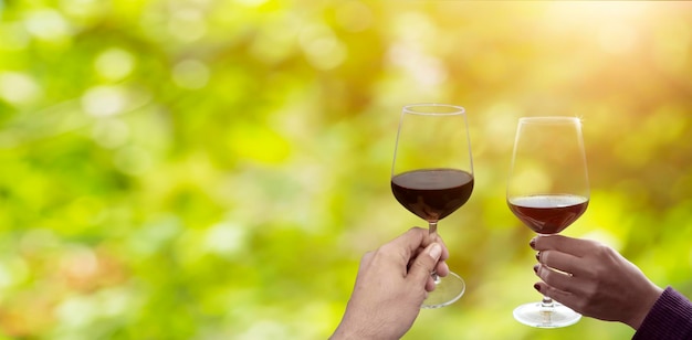 Mãos segurando um copo de vinho na frente do fundo desfocado