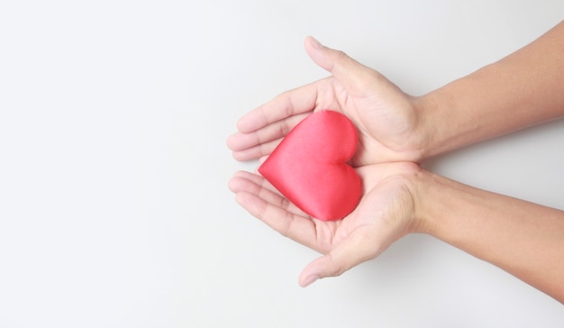 Mãos segurando um coração vermelho. conceitos de doação de saúde do coração