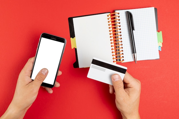 Mãos segurando um notebook e telefone simulado