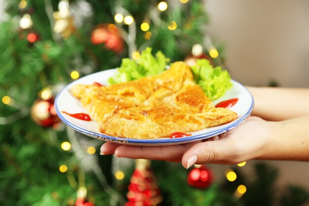 Mãos segurando um prato com hachapuri caseiro, no fundo brilhante