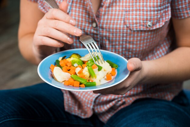 Mãos segurando um prato de legumes