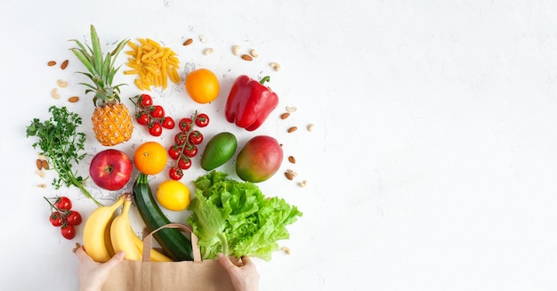 Mãos segurando um saco de papel com comida vegetariana saudável