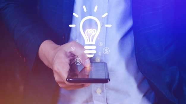 Mãos segurando um smartphone com lâmpada Lâmpada de ideia brilhante para conceito novo conceito de ideia com tecnologia de inovação e inspiração no conceito de ciência e comunicação