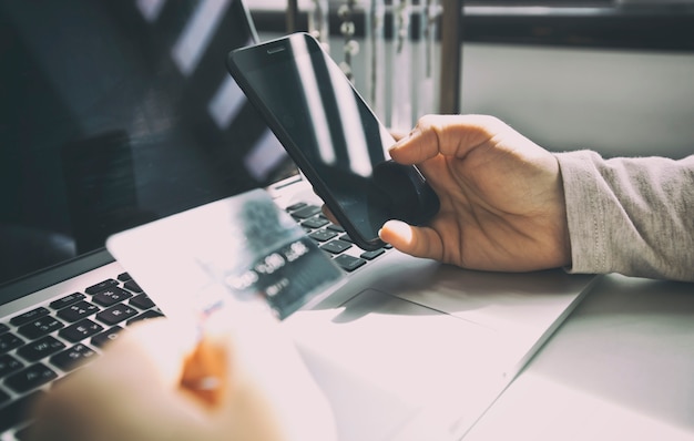 Mãos segurando um smartphone e cartão de crédito