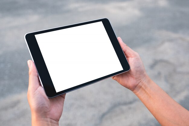 Mãos segurando um tablet pc preto com uma tela branca em branco