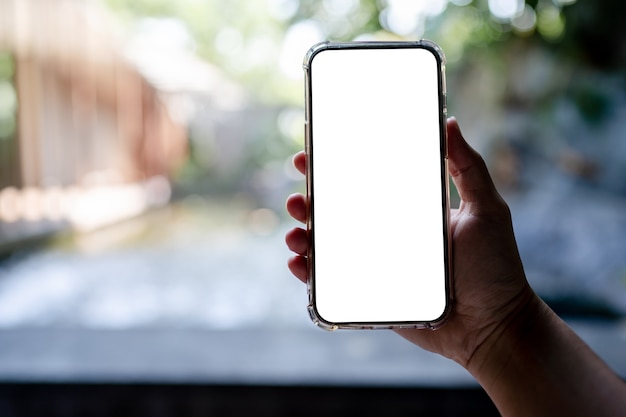 Mãos segurando um telefone celular branco com simulação de tela em branco, plano de fundo do hotel spa.