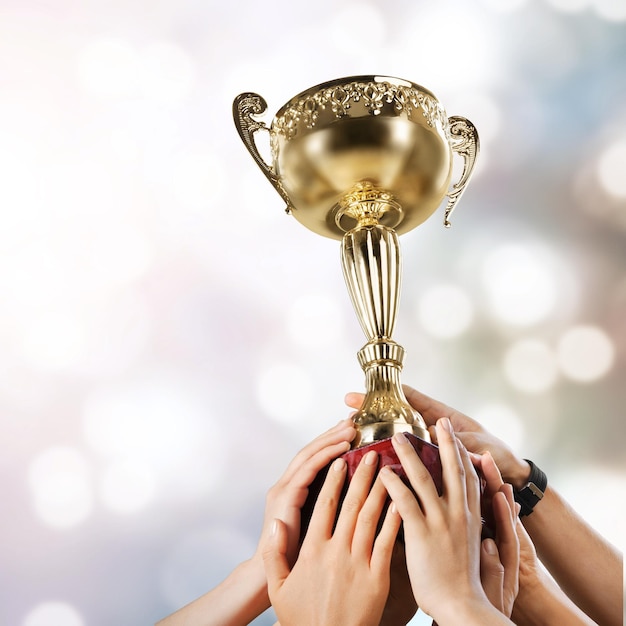 Mãos segurando um troféu de campeão dourado