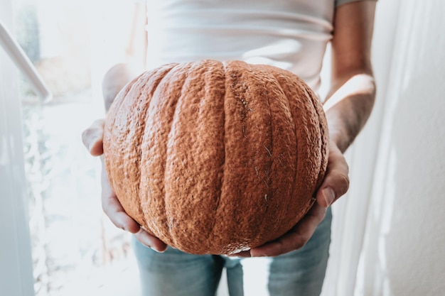 Mãos segurando uma abóbora super texturizada se preparando para o halloween. Trabalho e atividades manuais em casa, conceito de festa em casa. Fechar imagem