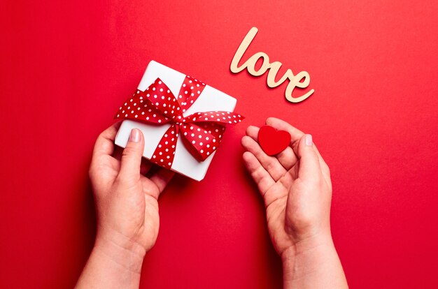 Mãos segurando uma caixa de presente com um pequeno coração vermelho
