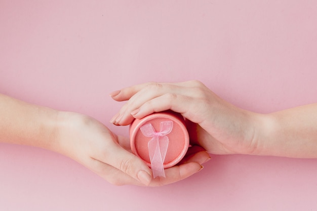 Mãos segurando uma caixa de presente rosa