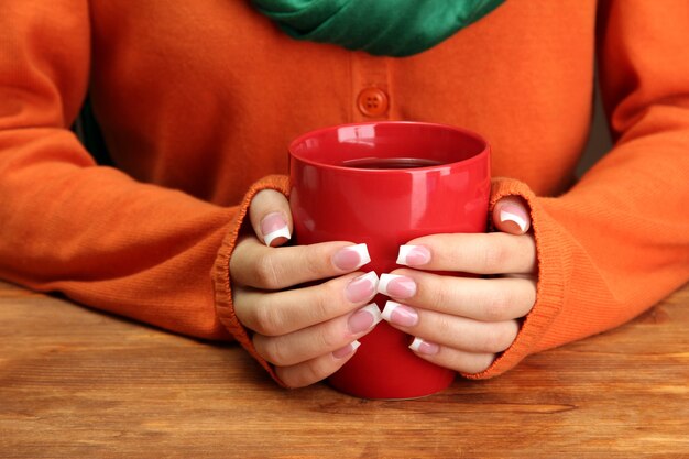 Mãos segurando uma caneca com close-up de bebida quente