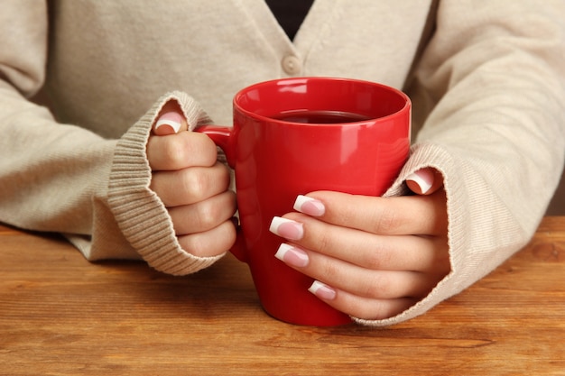 Mãos segurando uma caneca de bebida quente, close-up