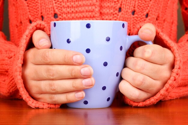 Mãos segurando uma caneca de bebida quente, close-up