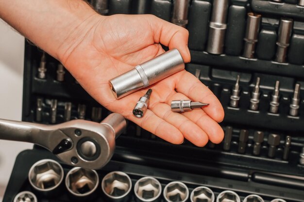 Mãos segurando uma chave de ferramentas e porcas no fundo de uma caixa para um motorista