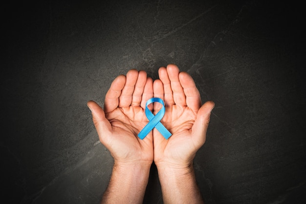 Mãos segurando uma fita de câncer de próstata, conceito de câncer de cólon, fita azul