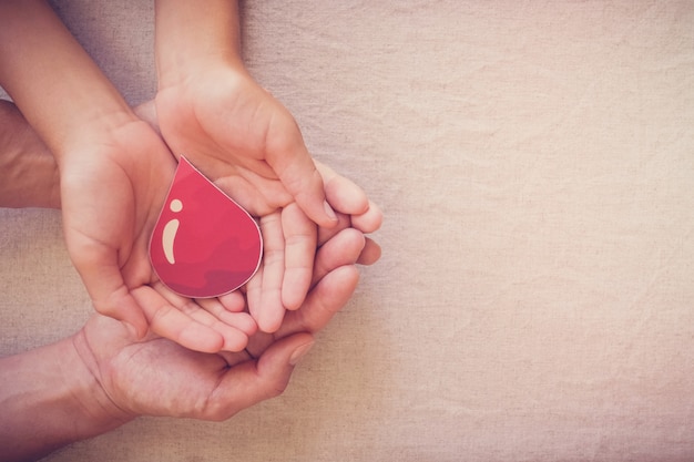 Mãos segurando uma gota de sangue, conceito de dia mundial do doador de sangue