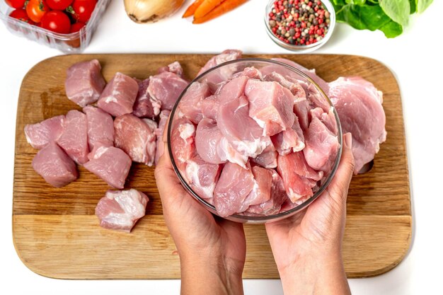 Mãos segurando uma tigela de vidro com pedaços picados de carne crua vista superior