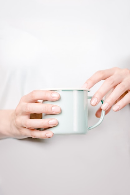 Foto mãos segurando uma xícara de esmalte de menta