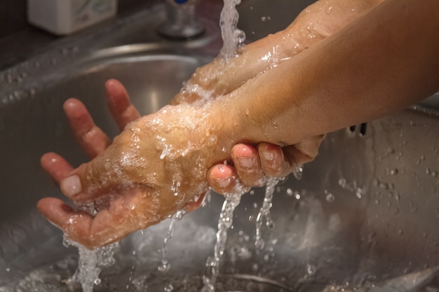 Mãos sendo lavadas sob fluxo de água da torneira