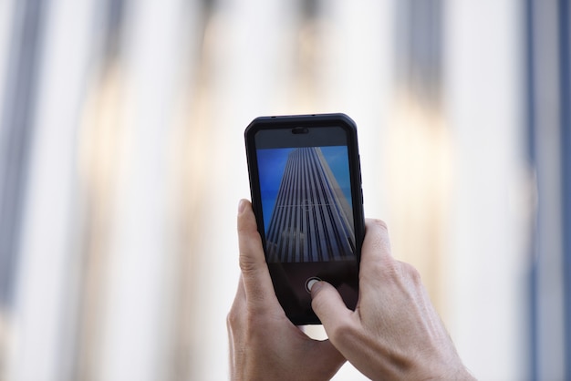 Mãos tirando uma foto com um telefone celular na cidade