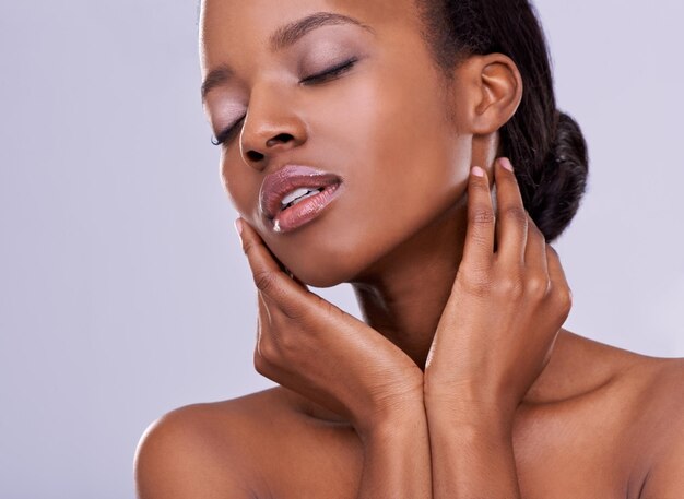 Mãos tocando rosto e mulher negra com beleza natural cosméticos e bem-estar com maquiagem em fundo branco cuidado da pele saudável e dermatologia satisfação e calma para tratamento em estúdio