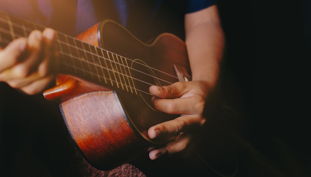 Mãos tocando violão ukulele acústico. Show de habilidades musicais