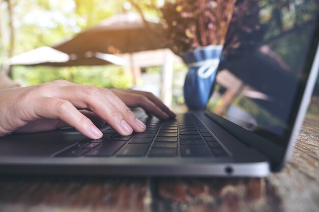 mãos trabalhando e digitando no teclado do laptop na mesa de madeira no café