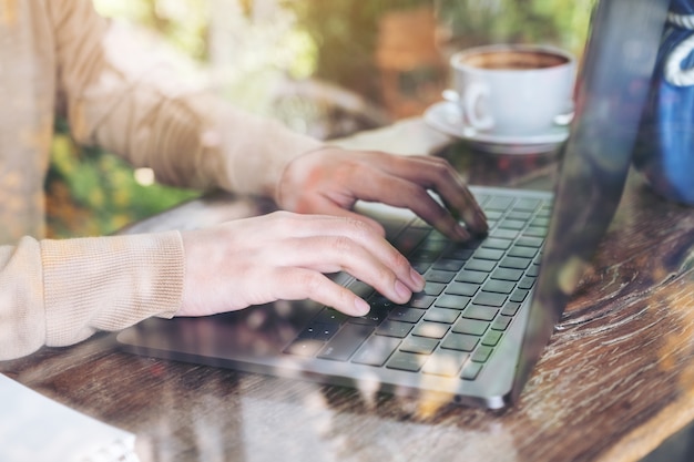 mãos trabalhando e digitando no teclado do laptop na mesa de madeira no café