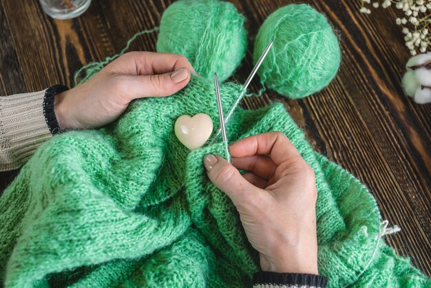 Mãos tricotando um suéter verde aconchegante