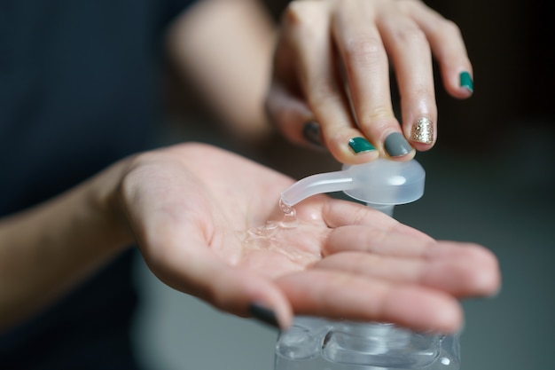 Mãos usando dispensador de bomba de gel de desinfetante para as mãos. Desinfetante transparente no frasco da bomba, para matar germes, bactérias e vírus.