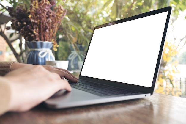 Foto mãos usando e digitando no laptop com tela de desktop branco em branco na mesa de madeira no café