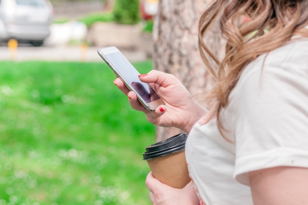 mãos usando um telefone de mensagens de texto no aplicativo de smartphone e segurando papel de café