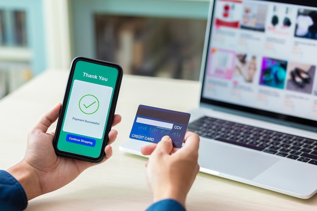 Mãos usando um telefone e cartão de crédito para pagamento on-line