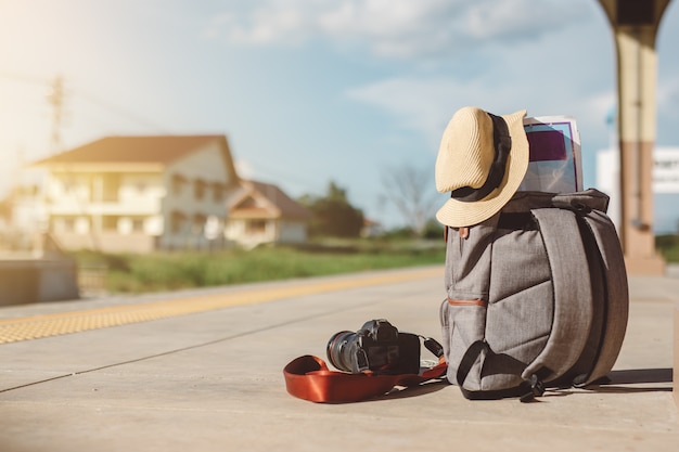 Foto mapa en mochila, teléfono móvil con auricular y sombrero en la estación de tren con un conjunto traveller.sun, concepto de viaje.