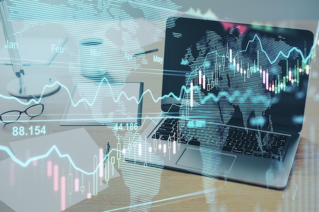 Mapa mundial y gráficos comerciales con una computadora portátil en el escritorio en segundo plano Comercio mundial y concepto de comunicación por Internet Doble exposición
