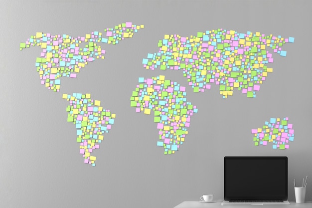 Mapa del mundo a partir de las pegatinas pegadas en la pared con una computadora portátil de pie al lado