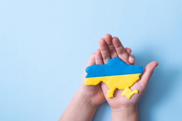Mapa ucraniano da bandeira das cores amarelo-azul na vista superior das mãos das crianças