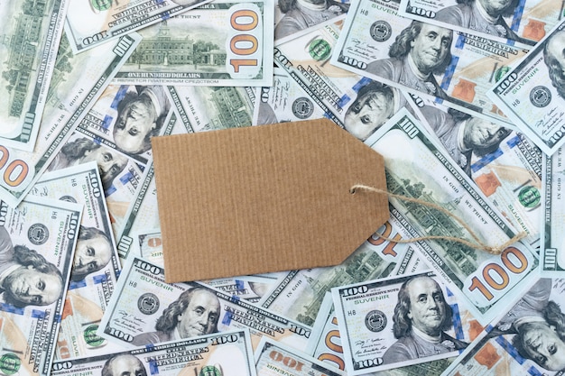 Maqueta de la bandera de compras con etiqueta de cartón sobre fondo de billetes de dólar dinero