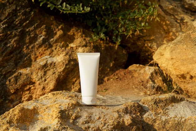 Foto maqueta blanca de un tubo de crema de bronceado o protección solar en piedra caliza amarilla junto al mar el concepto de cosméticos naturales