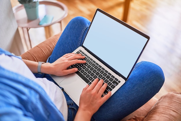 Maqueta en blanco de la pantalla de la computadora. Manos femeninas escribiendo en el teclado del ordenador portátil con fondo blanco para publicidad. Copia espacio