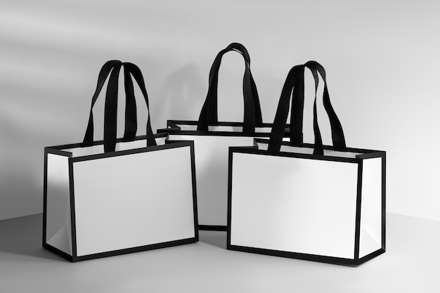 Maqueta de una bolsa de papel blanco con borde negro y mangos de tela negra