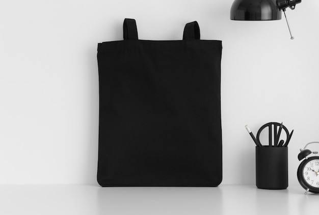Foto maqueta de bolso de mano negro con accesorios de espacio de trabajo en una mesa blanca