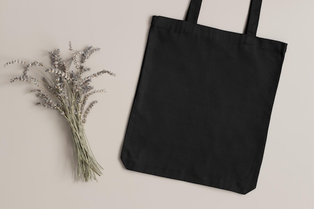 Foto maqueta de bolso de mano negro con una decoración de lavanda en el fondo beige