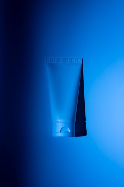 Maqueta de botella de plástico blanca para la marca de medicamentos o cosméticos crema gel cuidado de la piel pasta de dientes recipiente de botella cosmética en un fondo de neón azul minimalismo