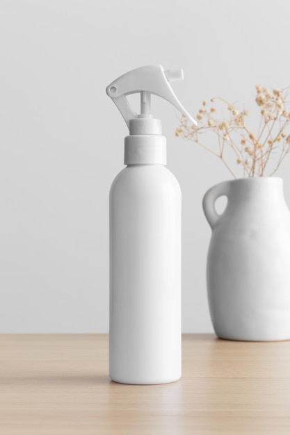 Maqueta de botella de rociador de gatillo cosmético blanco con una gypsophila en la mesa de madera