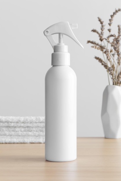 Maqueta de botella de rociador de gatillo cosmético blanco con lavanda y toallas en la mesa de madera