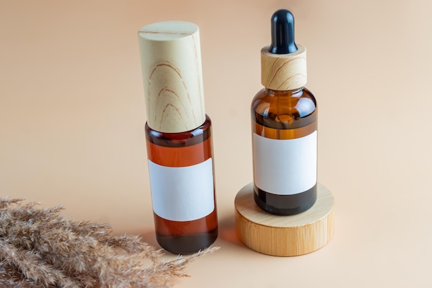 Una maqueta de botellas de cosméticos marrones con dispensador y etiqueta blanca y botella con pipeta en podio de madera para fotografía de cosméticos sobre fondo beige