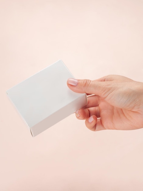 Maqueta de caja de paquete de producto blanco en blanco En una mano femenina Plantilla de embalaje de contenedor en blanco Caja de cartón blanca