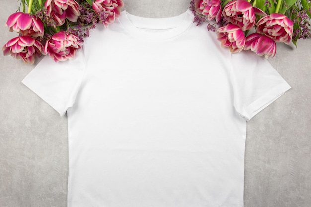 Maqueta de camiseta de algodón blanco para mujer con flores de tulipanes rosas sobre fondo de hormigón gris Plantilla de camiseta de diseño maqueta de presentación de impresión Vista superior plana